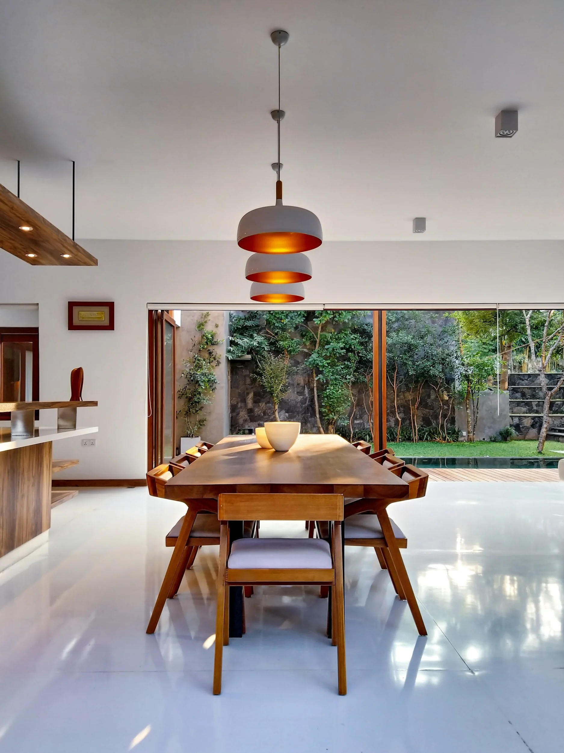 Sunlit dining room with custom wood table and brass pendants